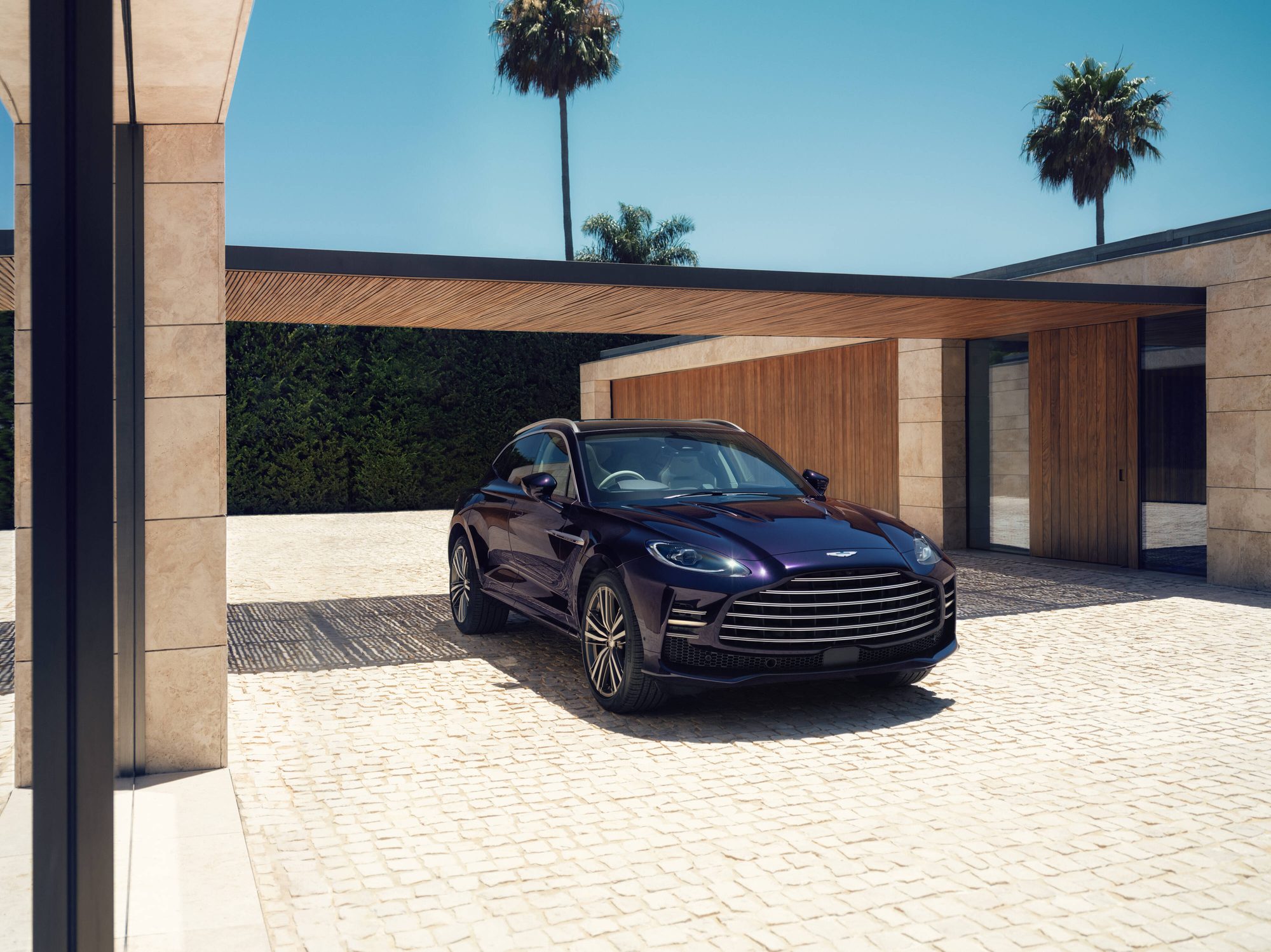 Aston Martin DBX GT morado oscuro estacionado frente a una casa moderna