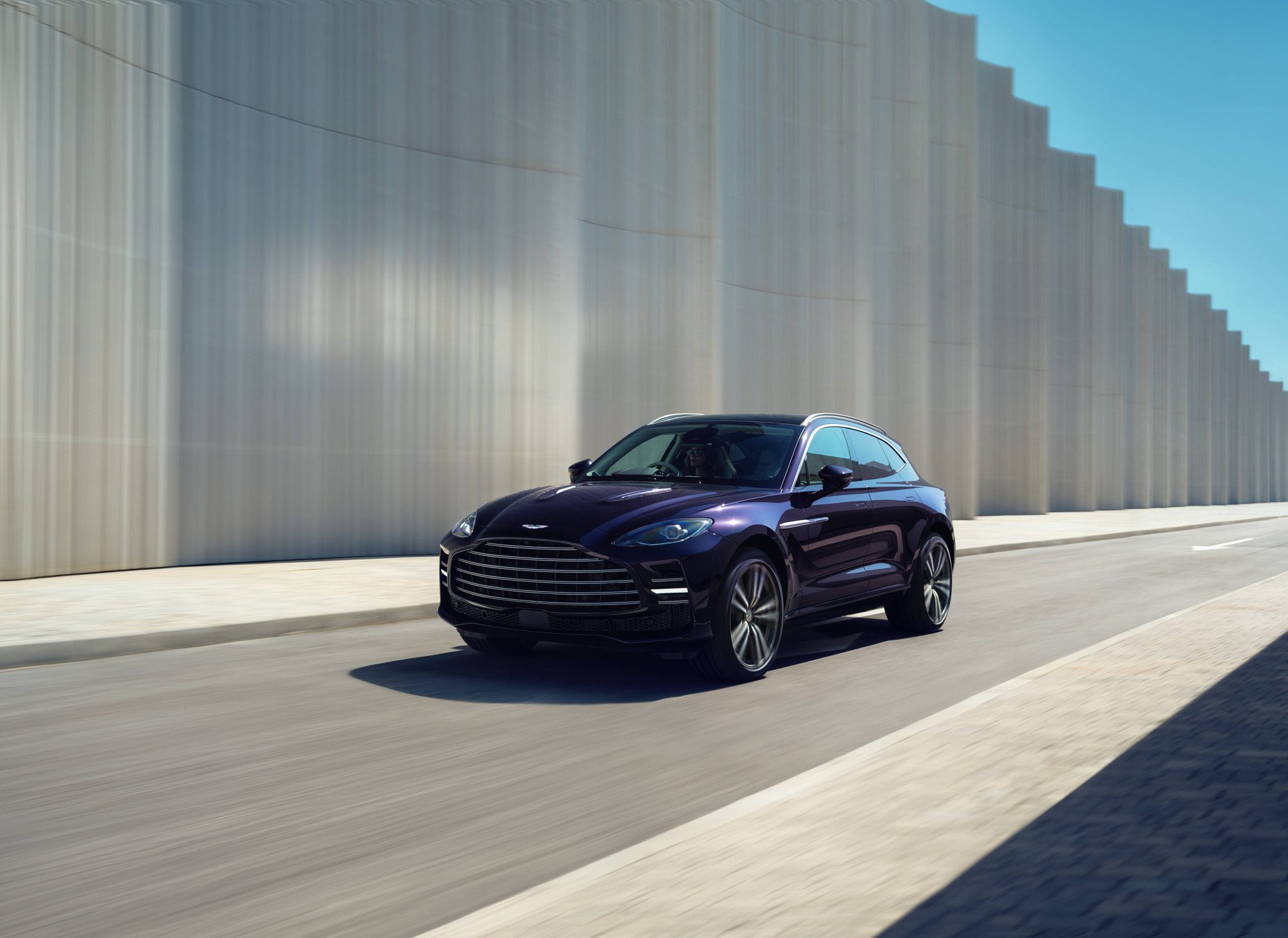 Aston Martin DBX GT circulando junto a un muro moderno