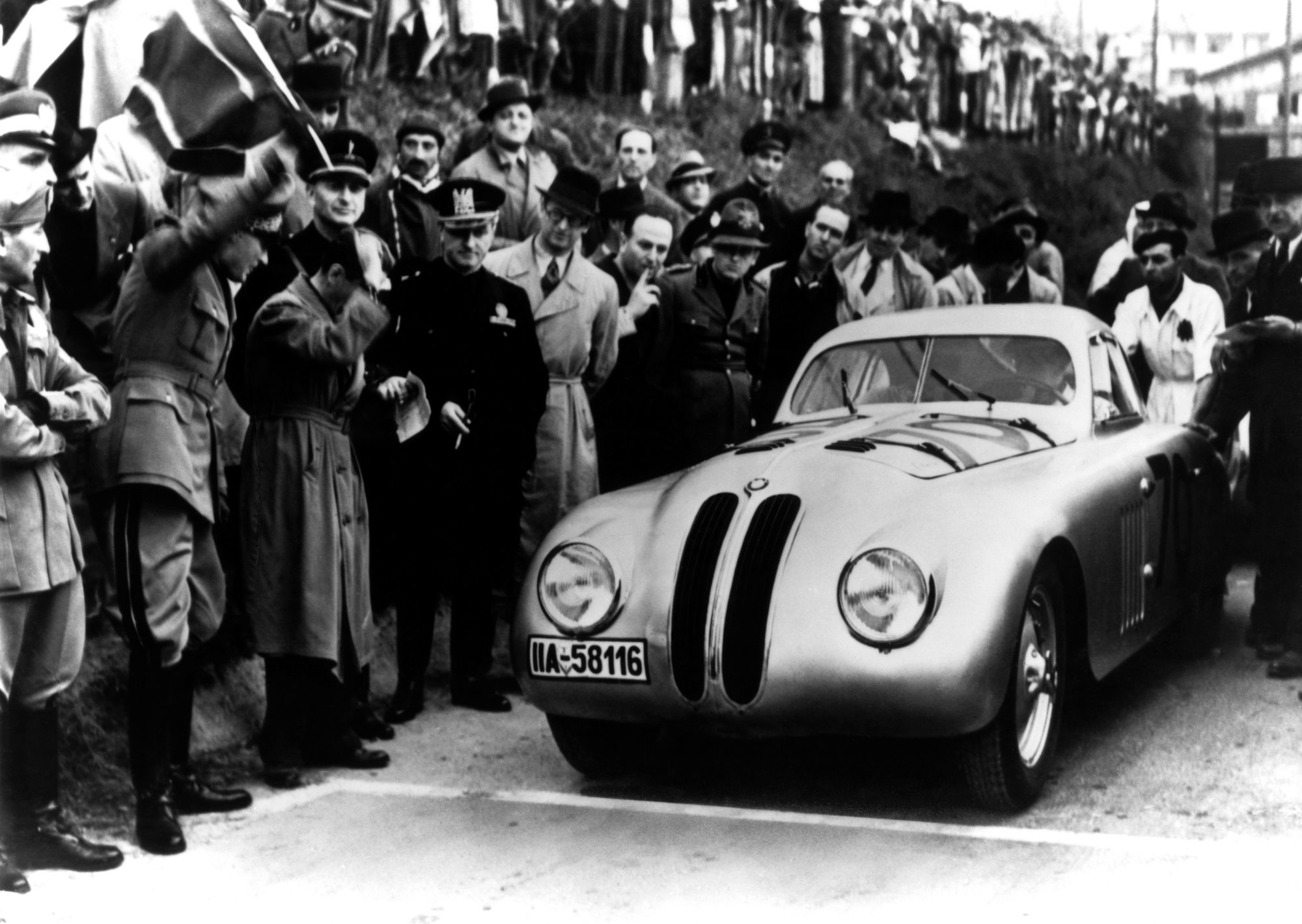BMW 328 Touring Coupé rodeado de público en una foto histórica en blanco y negro