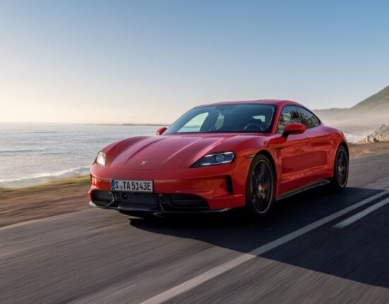 Porsche Taycan rojo circulando por una carretera costera