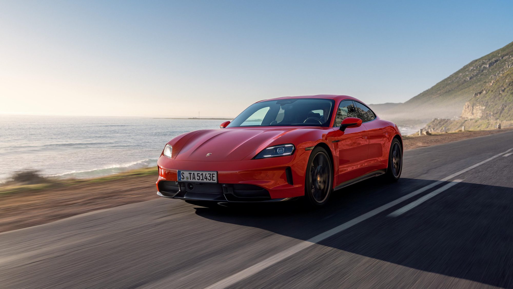 Porsche Taycan rojo circulando por una carretera costera