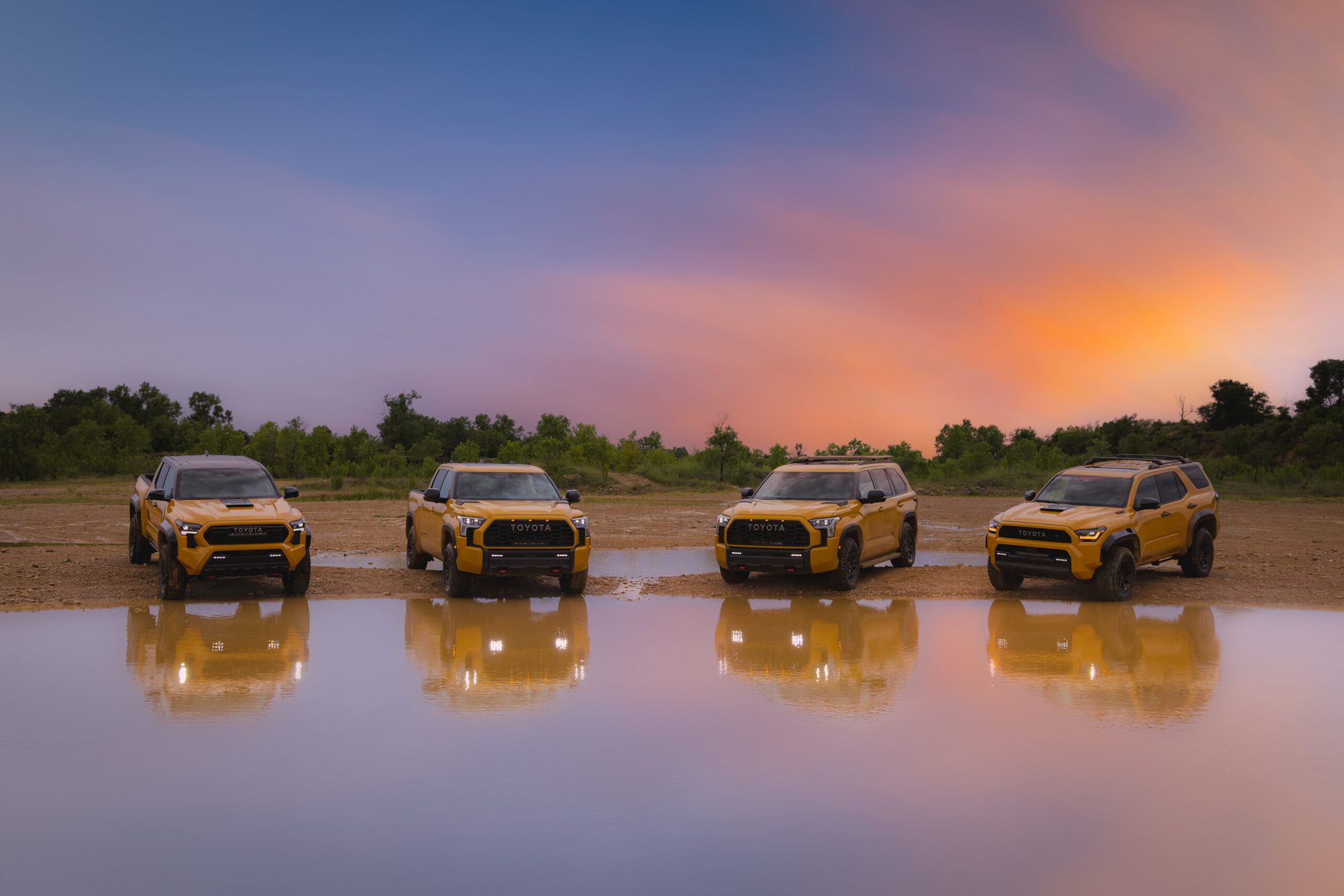 Cuatro vehículos Toyota TRD Pro reflejados en el agua al atardecer